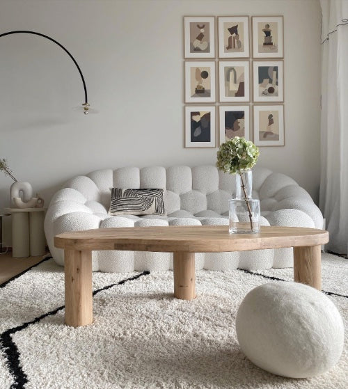 Canapé et pouf Rousseau blanc crème dans un salon clair, table basse en chêne et tapis berbère — Orbe Paris