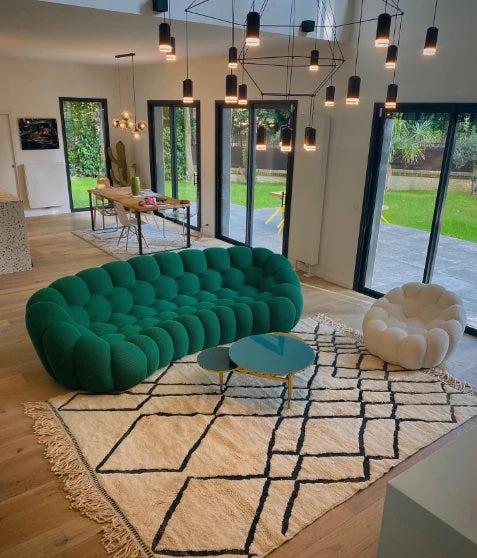 Canapé Rousseau vert profond et pouf blanc dans un séjour contemporain ouvert sur le jardin — Orbe Paris